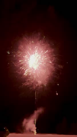 Brilliant red fireworks burst in the night sky, creating a dazzling display of light and color against the dark backdrop.