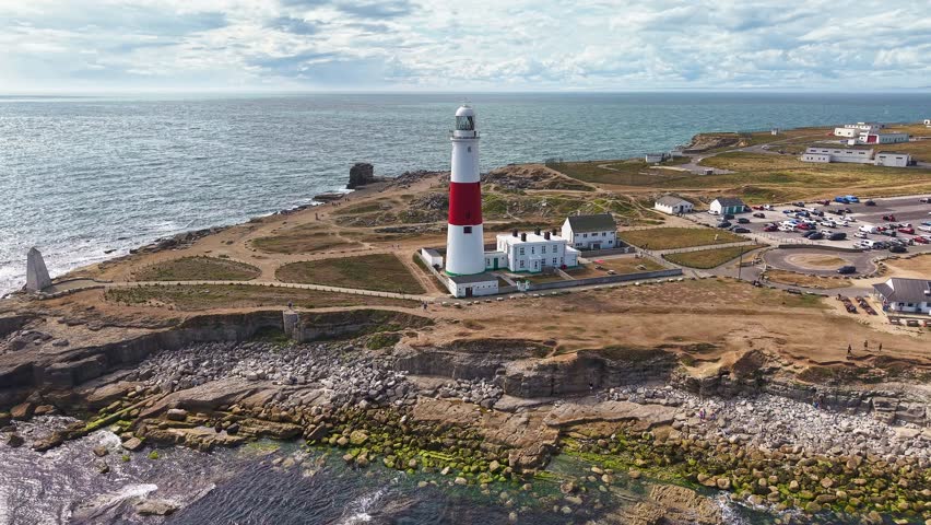 Aerial orbit of the iconic Portland Bill Lighthouse on the rocky Jurassic Coast, Dorset, UK.