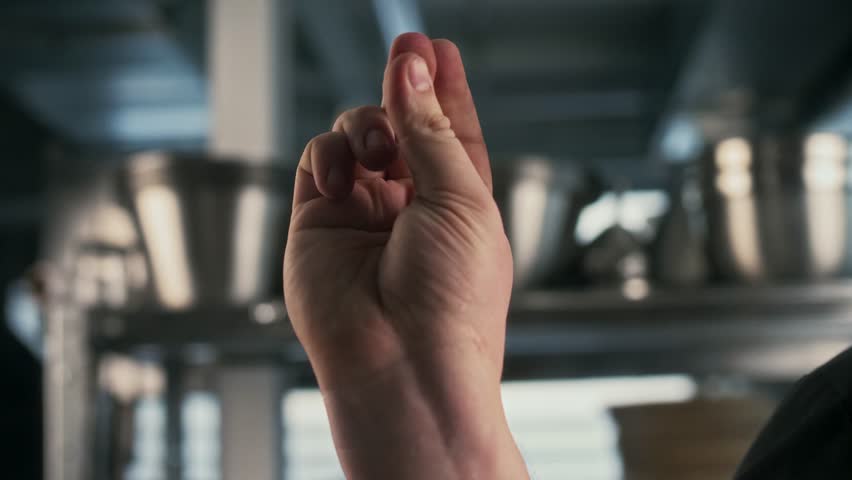 Close up of a man's hand snapping fingers in a professional commercial kitchen