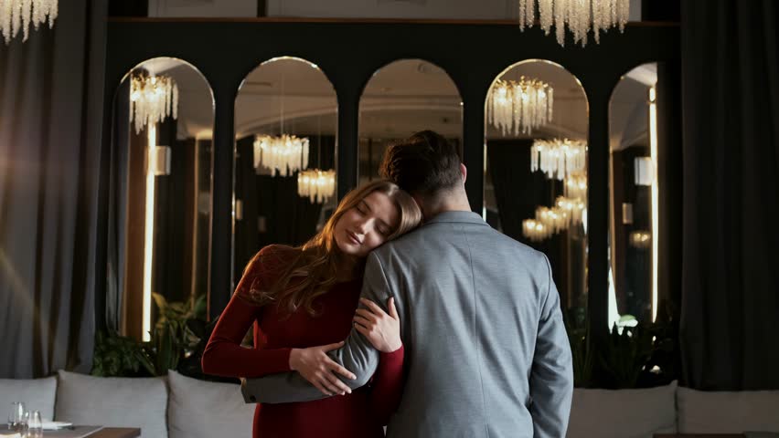 Cute young girl hugging her boyfriend in a nightclub with a luxurious interior