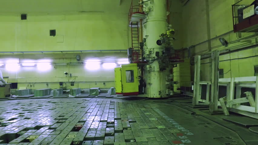 Panning shot of Chernobyl nuclear reactor with cleaning staff doing maintenance in HAZMAT suits in well lit laboratory. Pripyat, Ukraine