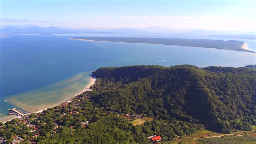 Coastal settlement at Ilha do Mel island nestled beside green forested hills and shoreline, Paraná, Brazil.