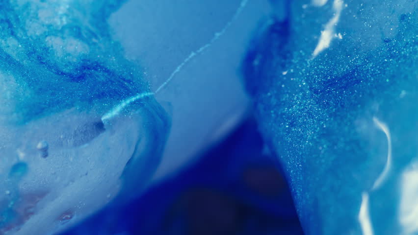 Shiny ink. Frost background. Defocused blue color sparkling droplets ice water floating on light creative acrylic cold abstraction.