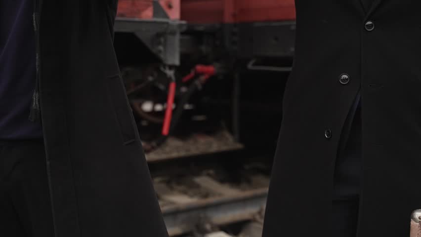Two gangsters in black coats take off their hats close-up. Men in black clothes in autumn with hats in their hands