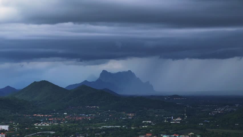 Dark monsoon clouds unleash rain over tropical mountain valley in dramatic weather scene