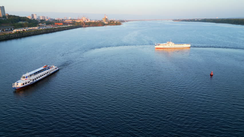 Passenger ferry navigating river at sunrise near city coastline. Clip