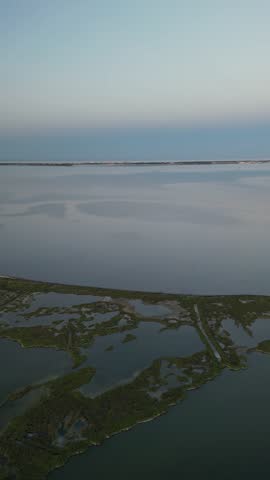 Aerial view of the tranquil waters meeting the horizon under a soft sky, a serene landscape of Etang de Leucate, Etang de Leucate, Occitanie, France.