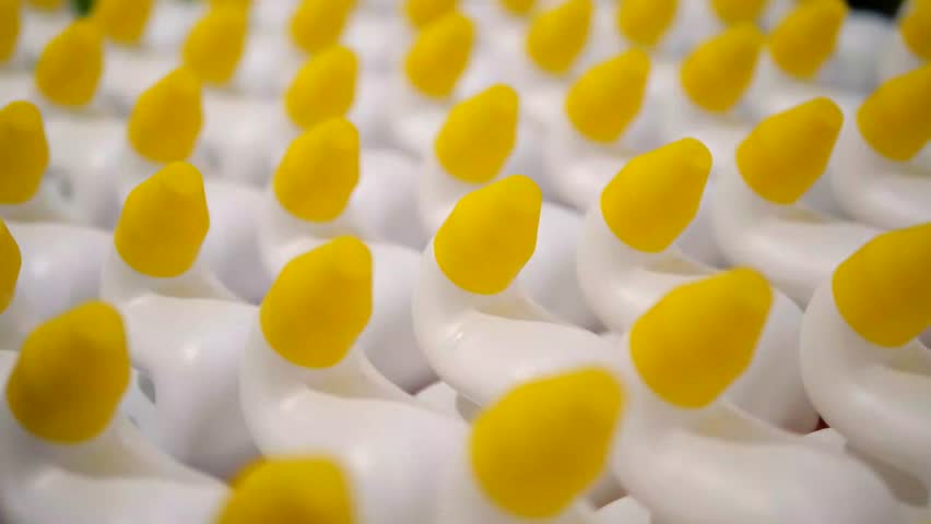 Close-up of modern household chemical bottles with ergonomic curved necks and contrasting yellow caps. 