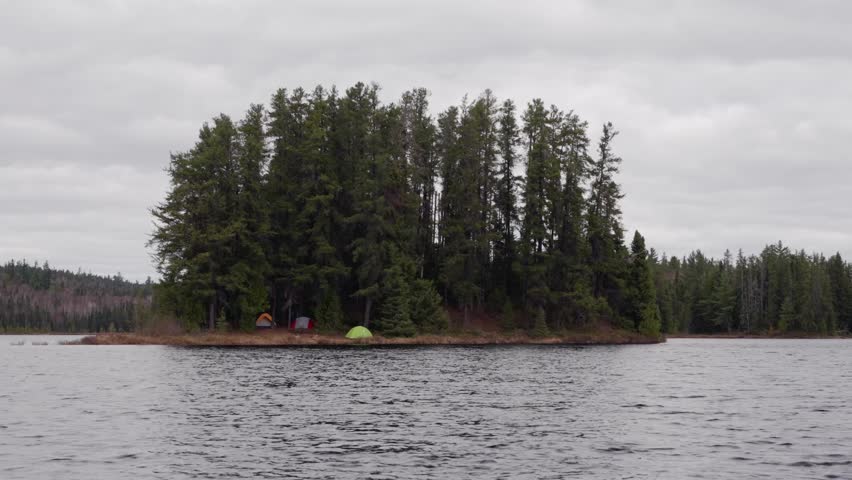 An island campsite rests on a quiet freshwater lake in Timmins, Northern Ontario, Canada on a gloomy spring day