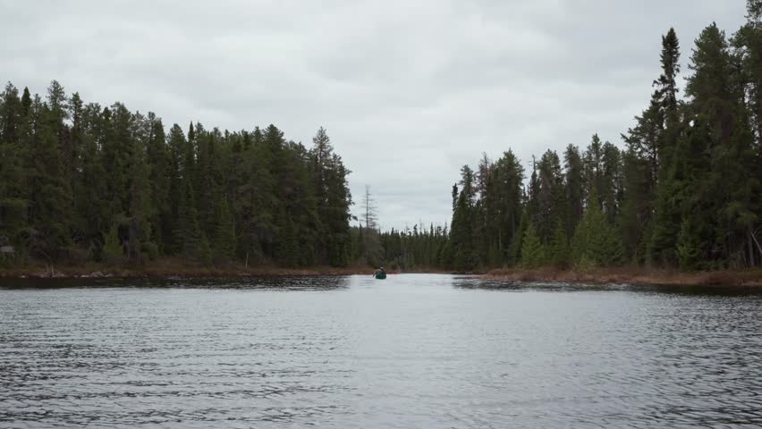 Two canoeists paddle a narrow lake channel in Timmins, Ontario