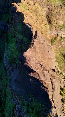A vertical aerial view of hikers walking through the Pico do Arieiro to Pico Ruivo hike trail at sunrise in Madeira