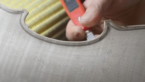 Skilled luthier carefully refining violin surface with specialized knife, demonstrating intricate woodworking techniques and meticulous craftsmanship in instrument making process - Powered by Shutterstock - Get 15% off with code: PIKWIZARD15