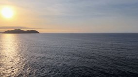 Aerial drone footage of the ocean at sunset, with golden sunlight reflecting on the waves as they crash against the rugged coastline, creating a peaceful yet dramatic seascape. - Powered by Shutterstock - Get 15% off with code: PIKWIZARD15