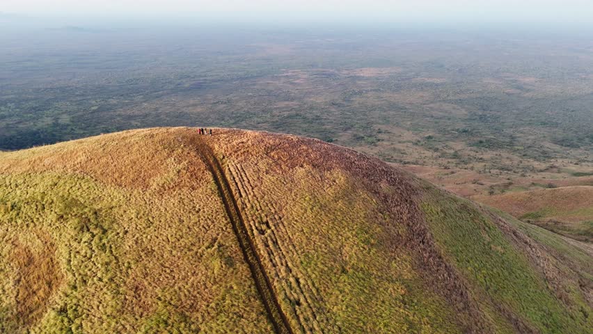 A top-down view of a grassy hill trail curving toward a summit in Chyulu Hills National Park, Kenya