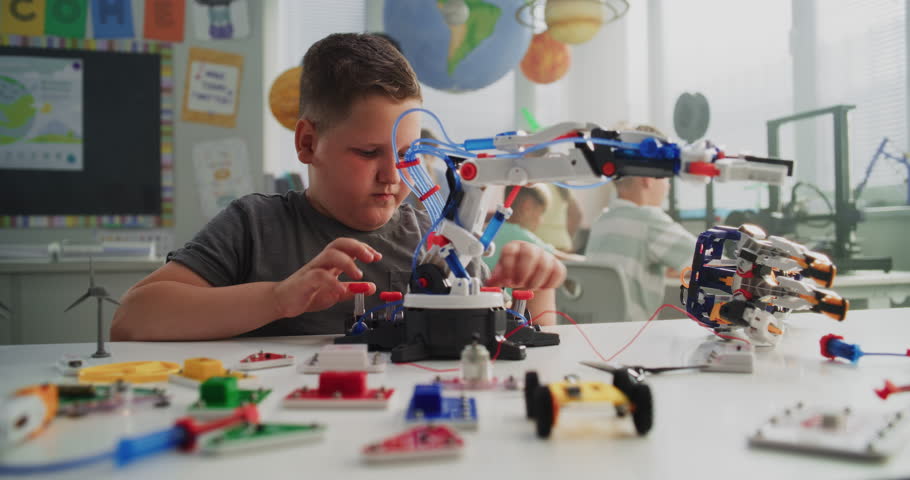 Talented Young Boy Studying Robotic Arm Model. Primary School Student Learning Science and Robotics Technology in Modern Classroom, Dreaming to Become Engineer. Creative Activity, STEM Education.
