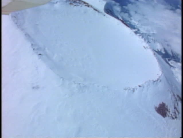 Aerial over the top of the volcanic crater on Mount Rainer, covered in snow