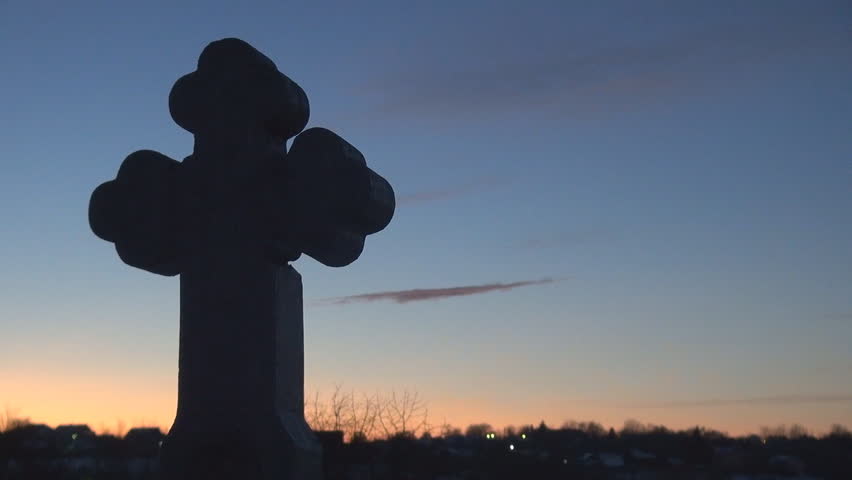 Cross in cemetery at sunset during winter time