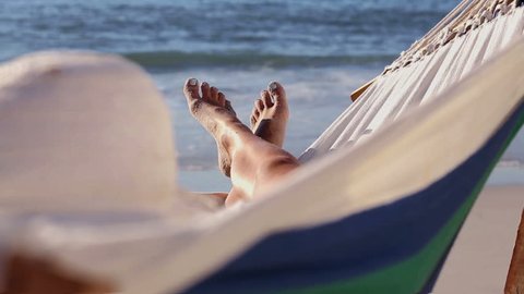 Woman relaxing on the beach in a hammock in front of the sea