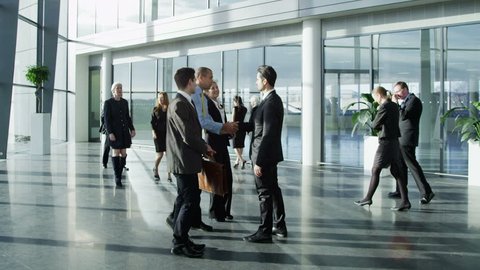 Confident and attractive young business team meet up with their client and shake hands, in a light and modern office building. 