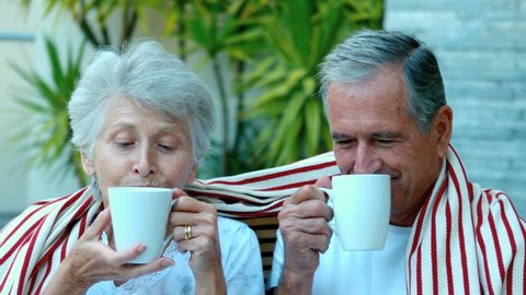 Retired couple enjoying coffee outside in slow motion