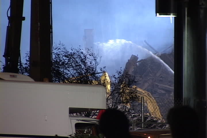 NEW YORK CITY - SEPTEMBER 28, 2001: Stream of water soaks World Trade Center rubble and silhouettes of pedestrians pass in foreground.