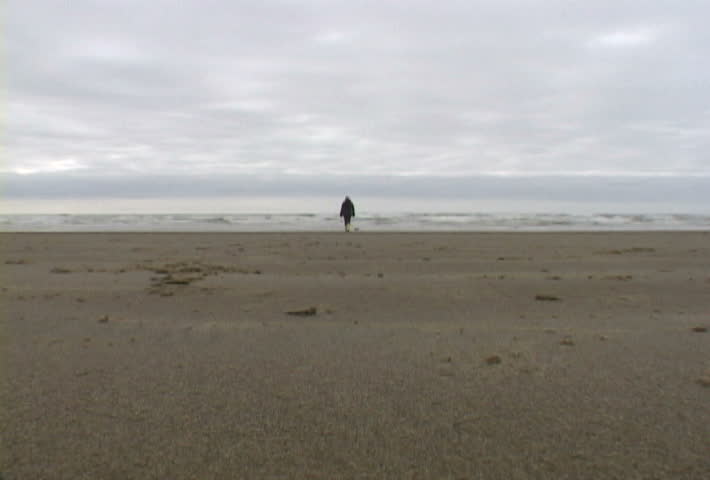 Woman at Haystack Rock in Cannon Beach, Oregon wearing yellow boots walks