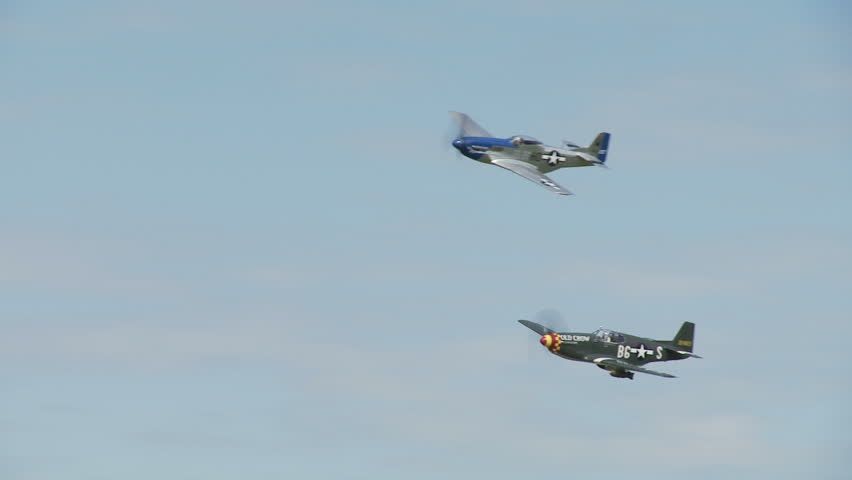 Two historic P-51 Mustang aircraft flying in formation.