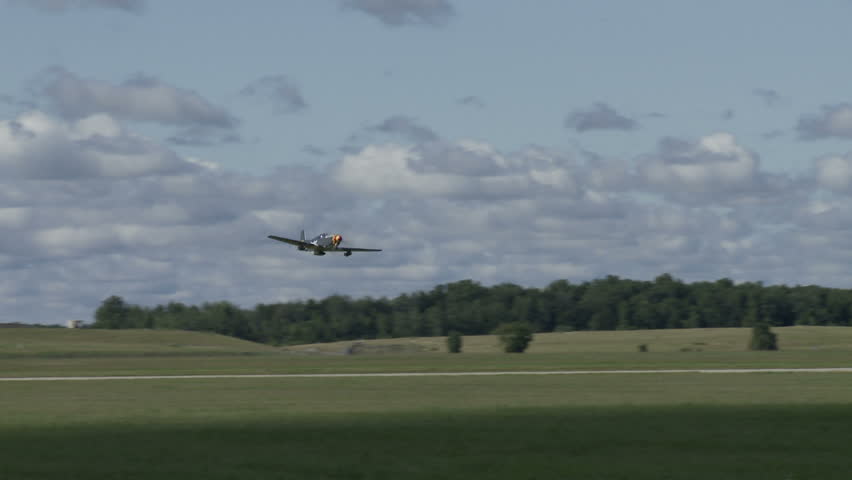 Historic P-51 Mustang aircraft flying low over an airfield.