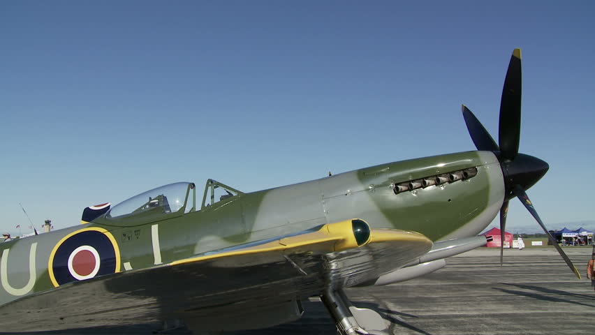 Two clips, dollying and panning across a parked Supermarine Spitfire fighter plane from World War II.