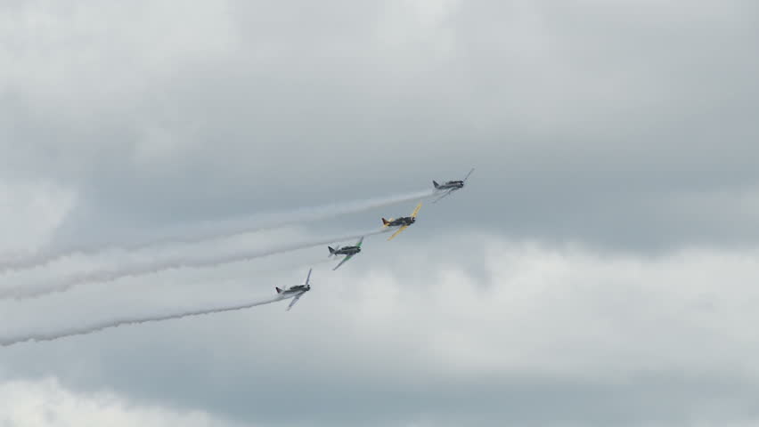 Four USAF T-6 Texans, training aircraft from WWII, performing stunts with smoke.