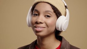 African teenage girl listening music,enjoying dance,headphones on beige backdrop - Powered by Shutterstock - Get 15% off with code: PIKWIZARD15