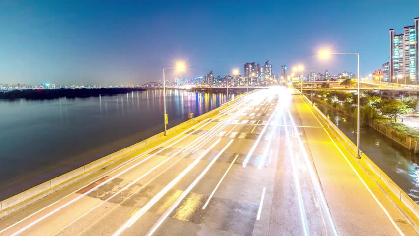 City skyline at night with traffic light trails on the highway and bridge
