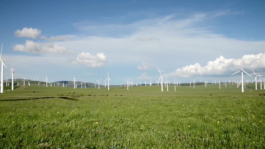 Wind turbine farm in a green field under a cloudy sky, generating clean energy