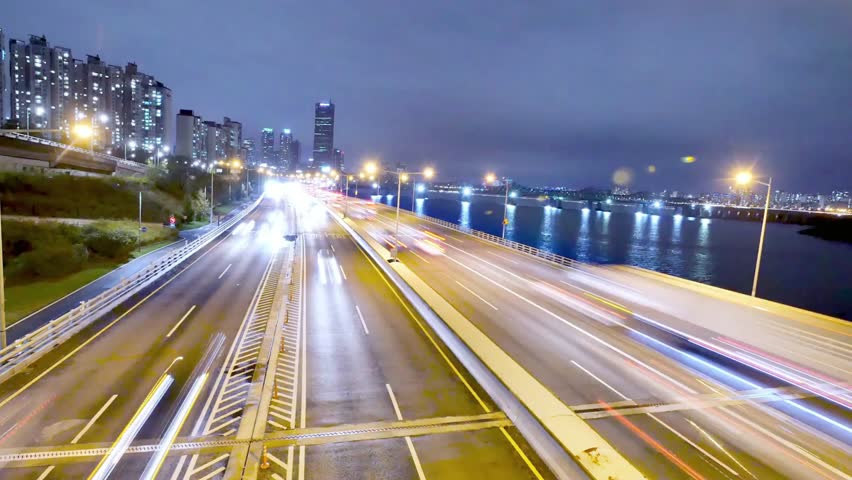 Night view of a city highway with blurred traffic lights and modern buildings