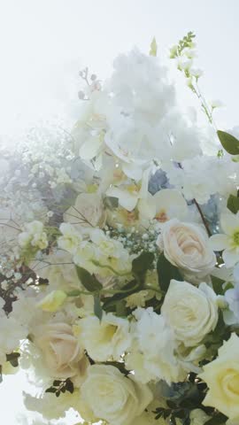 Wedding arch with flowers close-up, floral arrangement. Wedding ceremony decorated with white and blue flowers in open space, sun rays.