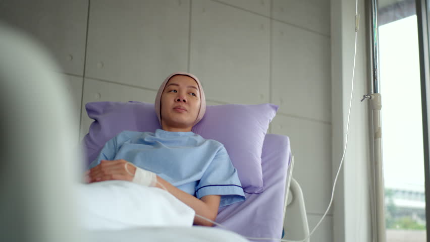 Asian patient woman with cancer smiling while resting on bed with positive
emotion and looking out the window after chemotherapy at hospital, cancer
female feeling calm and positive hope thinking.