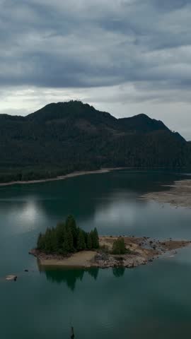 Aerial View of a Peaceful Lake Island, Forest, and Mountains in British Columbia, Canada