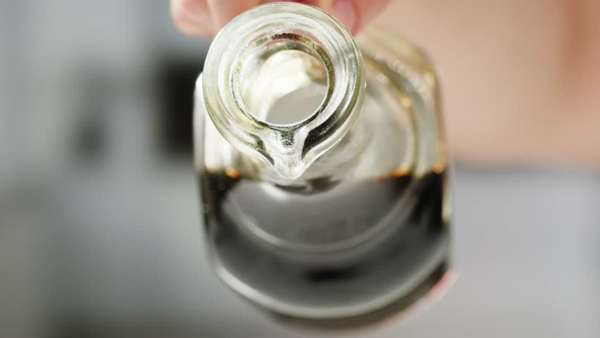 Asian Japanese soy sauce, Dark brown soy sauce pouring down into the glass bowl close up
