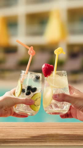 Fruit cocktail in hotel bar, Two cocktail glasses cheers in the hands on sea background. Bartenter making drink in bar, Summer vacation concept, A beautiful couple enjoy the vacation at the beach.