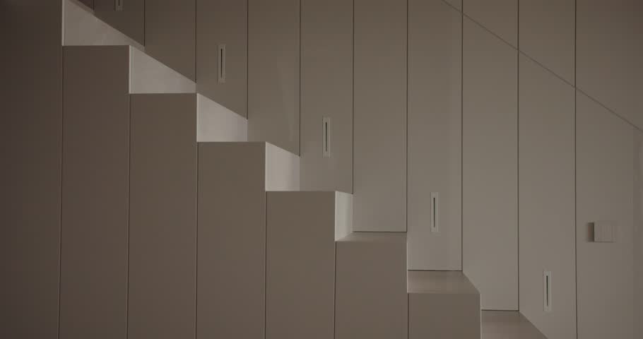 A woman stands barefoot atop geometric, cuboid structures within a monochrome, minimalist room, creating a serene and artistic scene. Woman Balancing on Cuboid Structures in a Minimalist Room