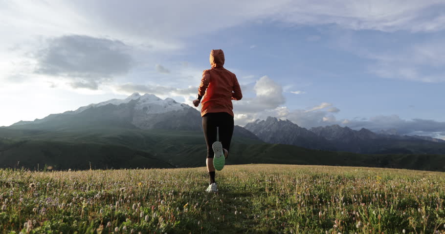 Trail runner running on the high altitude grassland mountain top, slow motion