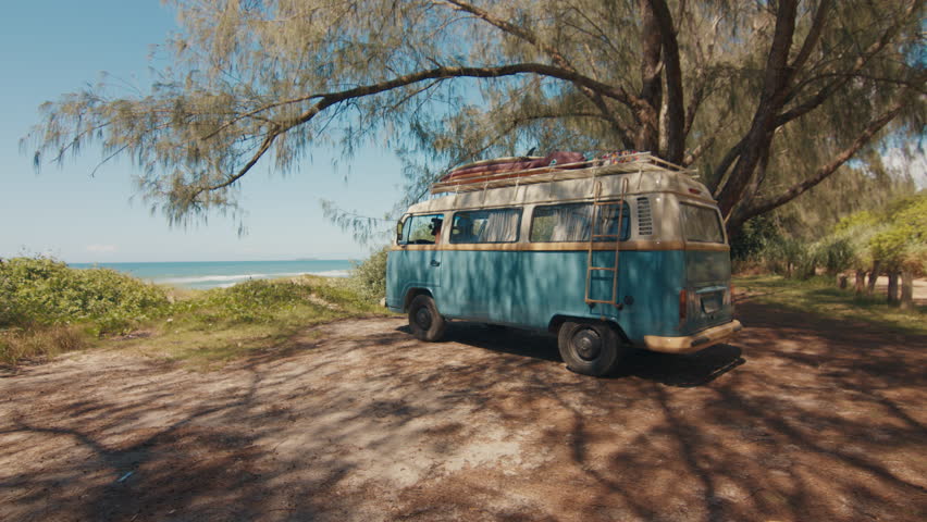 Hippies arrive to the surfing spot by retro classic hippie bus loaded with surfing boards. Hippies travel by retro bus in a search of a surfing spots