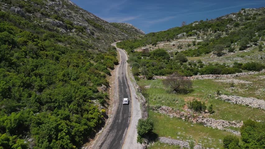 Drone view of a car traveling in a valley in Turkey. Curved road cuts through rugged terrain and nature. Explore the Turkish countryside off the beaten path....