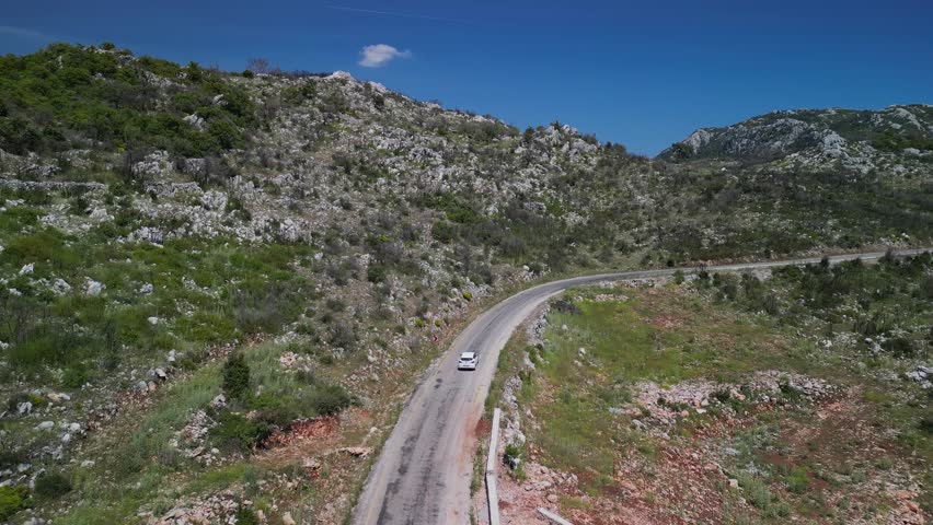 Vehicle ascends rocky terrain through Turkish hillsides. Dry shrubs and green patches mark this rugged Turkish trail. Turkey