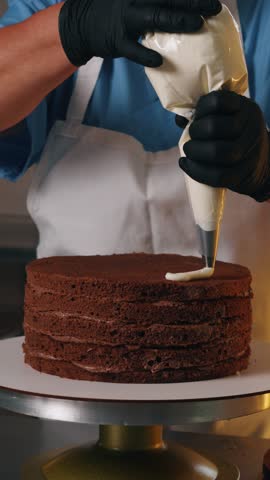 Close-up vertical video of a freshly baked layered cake being decorated with creamy white frosting and colorful sprinkles, creating a festive and appetizing dessert. Ideal for themes of baking, pastry