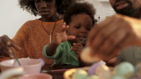 Family members creating colorful easter eggs together, sharing joyful moments while decorating in kitchen, engaging in festive springtime tradition - Powered by Shutterstock - Get 15% off with code: PIKWIZARD15