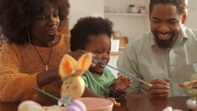 Family members joyfully painting colorful easter eggs together, sharing playful moments of creativity and bonding in kitchen interior - Powered by Shutterstock - Get 15% off with code: PIKWIZARD15