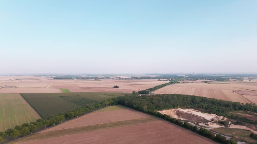 Aerial view of expansive rural landscape showcasing fields, forests, and horizon at sunrise.