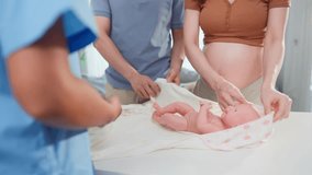 Pregnant woman and husband learn how to wrap a baby at maternal center. Young expectant couple smile with happiness while receiving guidance and prenatal education from nurse during checkup at clinic. - Powered by Shutterstock - Get 15% off with code: PIKWIZARD15