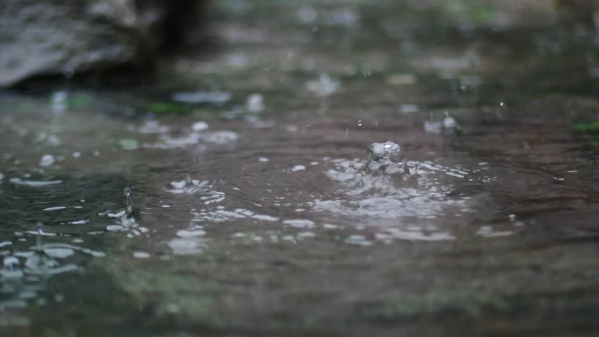 close up of raindrops with a rocky background.
